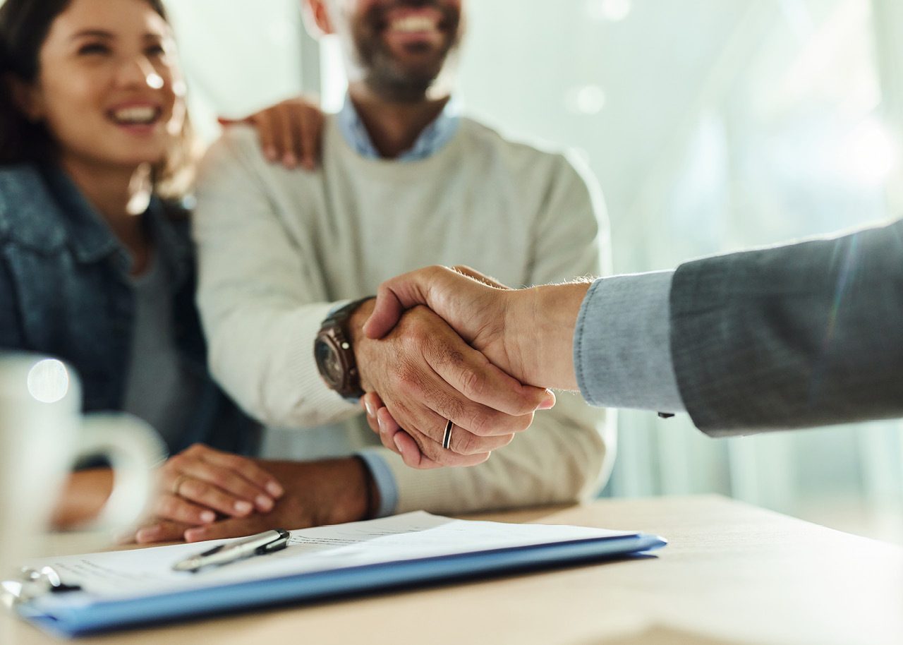 Advisor shaking hands with happy clients during a business meeting